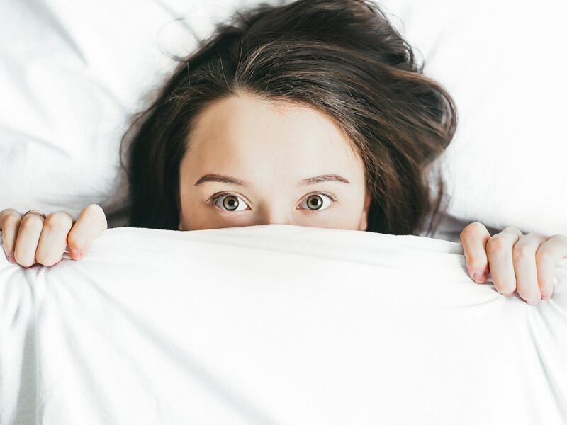 woman covering her face with blanket