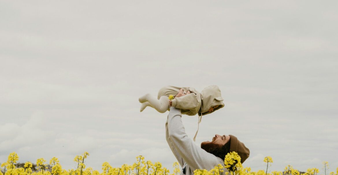 a person holding a baby in a field of yellow flowers