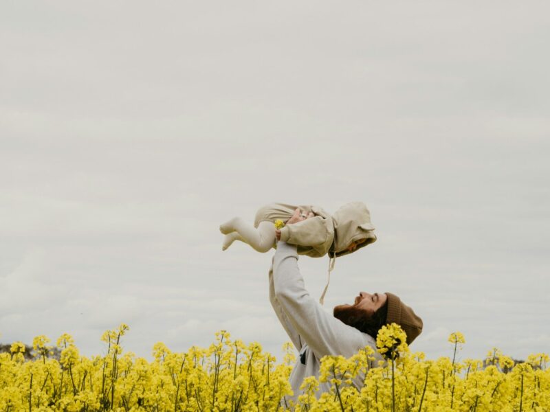 a person holding a baby in a field of yellow flowers